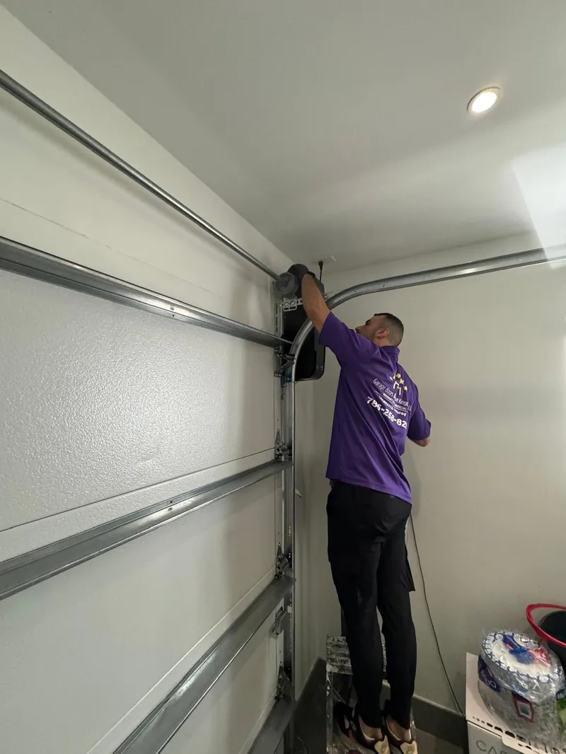 Garage Door Kingdom technician adjusting a residential garage door opener belt drive system during a routine maintenance visit