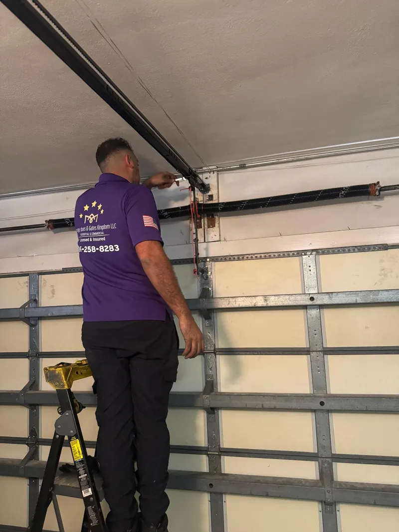 Garage Door Kingdom technician on ladder installing vertical garage door tracks in a Broward County, Florida home