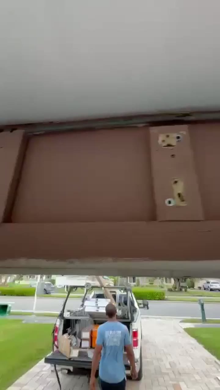 Garage Door Kingdom technician carrying a replacement garage door panel section in Broward County, FL